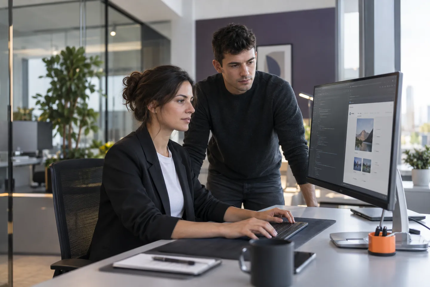 Due giovani professionisti verificano codice e anteprima di un’applicazione web su un monitor
