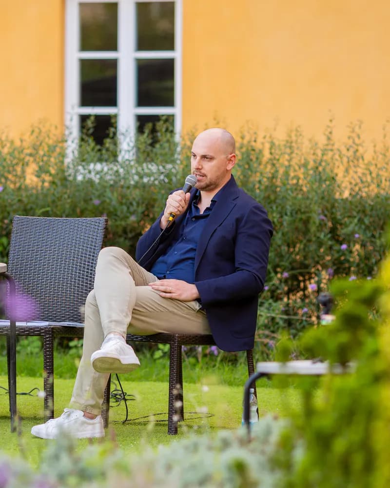 Gabriele Pecchioli al microfono, seduto nel giardino durante la presentazione del libro