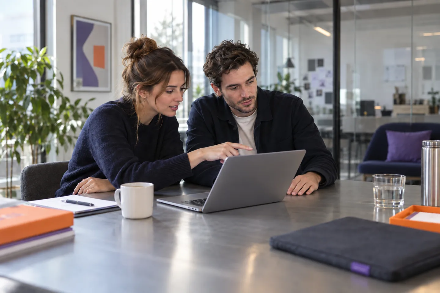 Due giovani professionisti esaminano un progetto sul portatile in uno studio contemporaneo