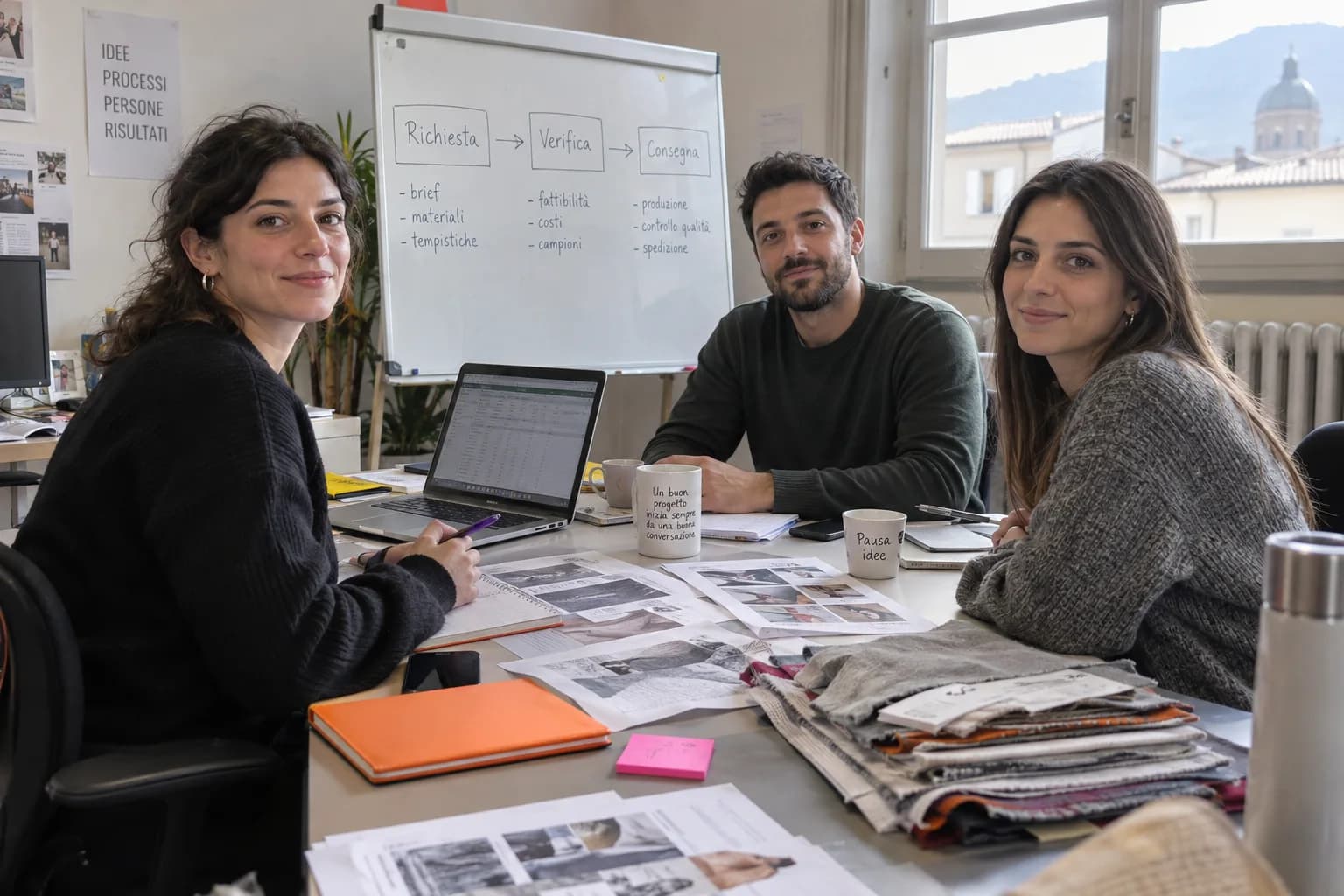 Tre giovani professionisti in un ufficio tessile italiano, fra campioni e una lavagna con le fasi del lavoro
