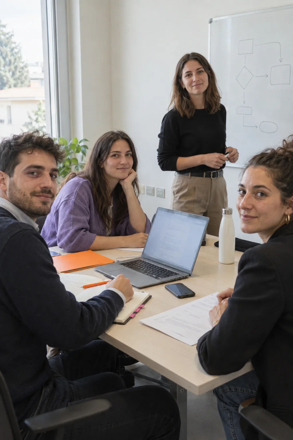 Scena illustrativa di un laboratorio aziendale: quattro giovani professionisti accanto a documenti e una mappa dei passaggi